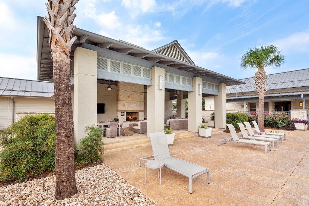 a patio with lounge chairs and a fire pit