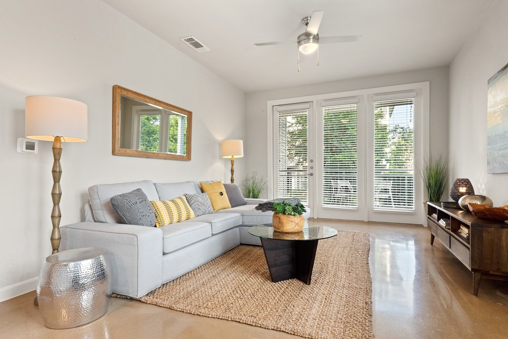 a living room with white walls and a white couch with yellow and gray pillows