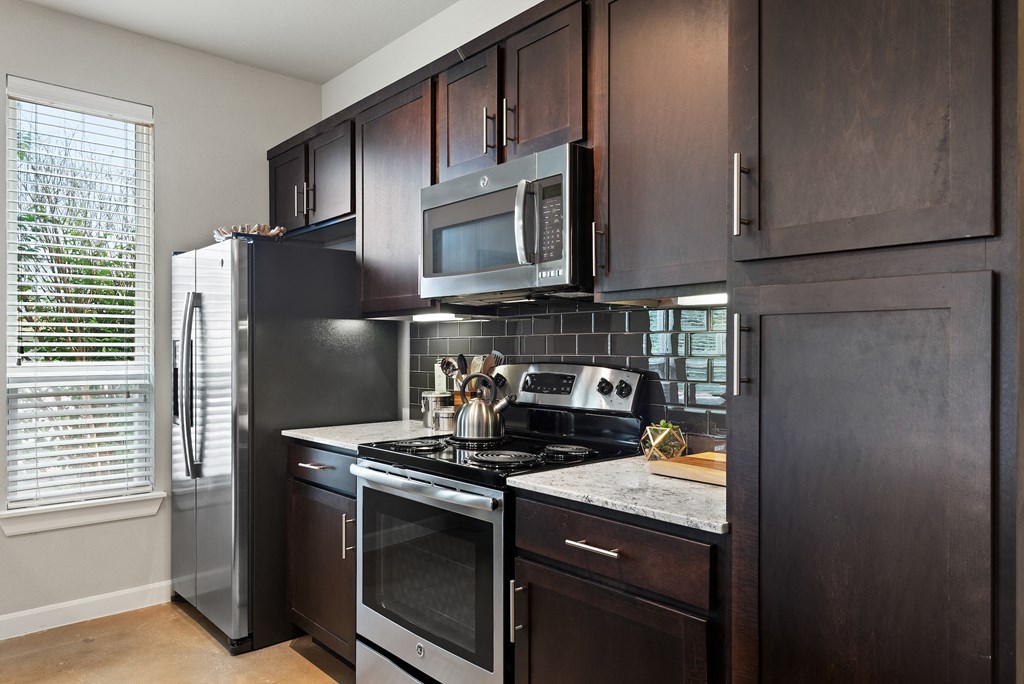 a kitchen with dark cabinets and white countertops