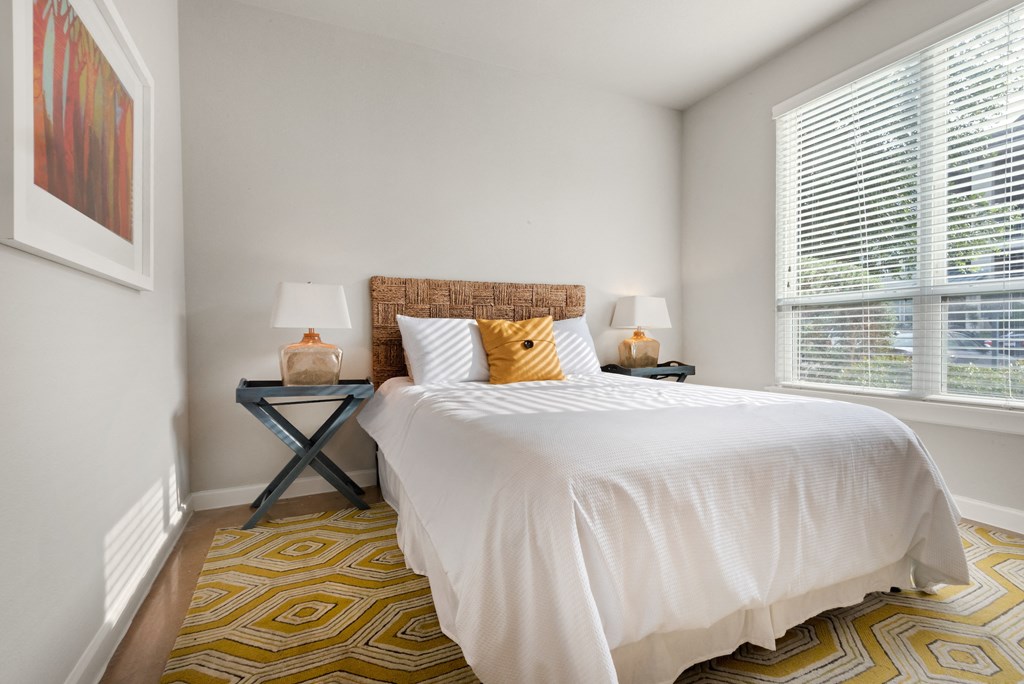 a bedroom with white walls and a yellow and white rug