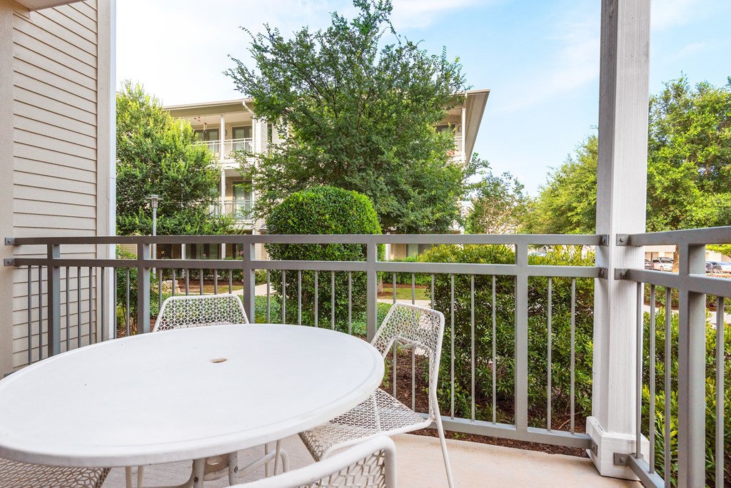 a white table and chairs sit on a balcony in front of an apartment building
