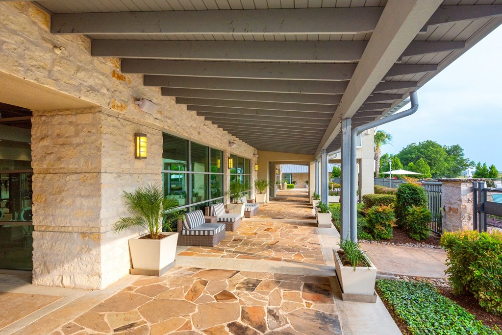 a covered walkway with benches and potted plants