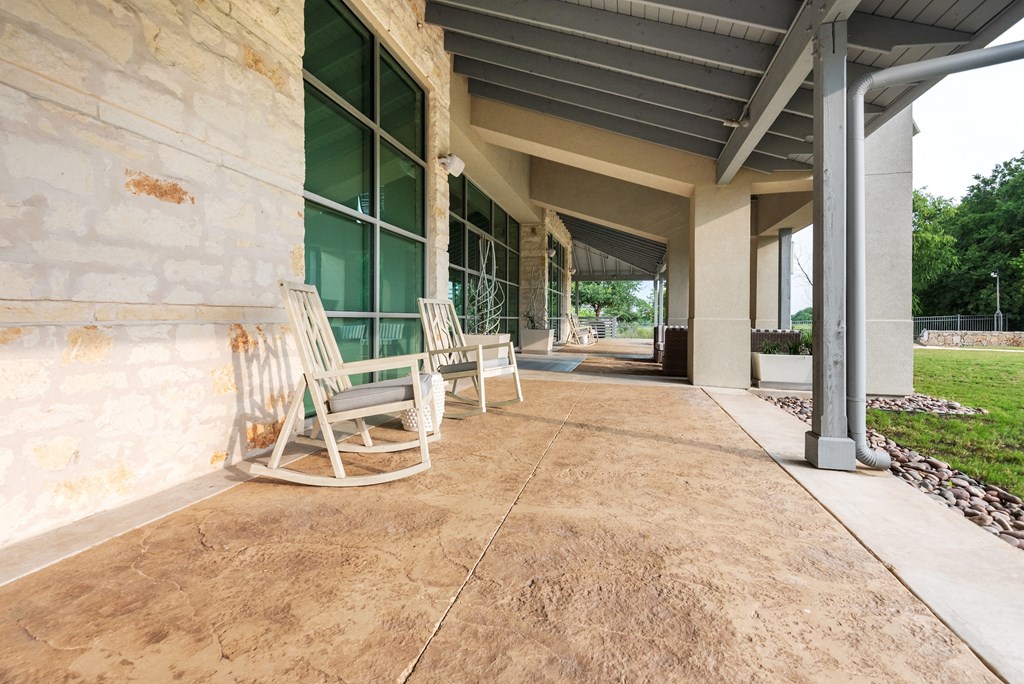 a pair of rocking chairs sit on a porch in front of a building
