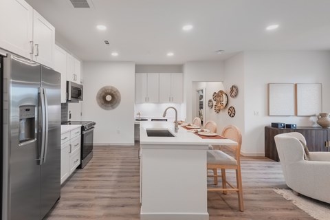 A modern kitchen with a stainless steel refrigerator and wooden flooring.