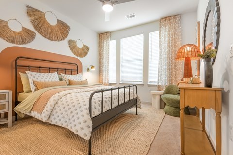 A bedroom with a bed, a chair, and a table with a lamp on it.