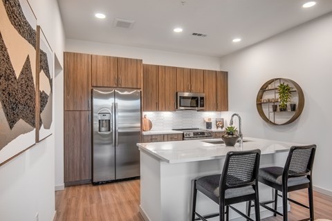 A kitchen with a refrigerator, microwave, and sink.