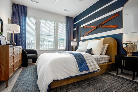 A bedroom with a bed, nightstands, and a window with blinds.