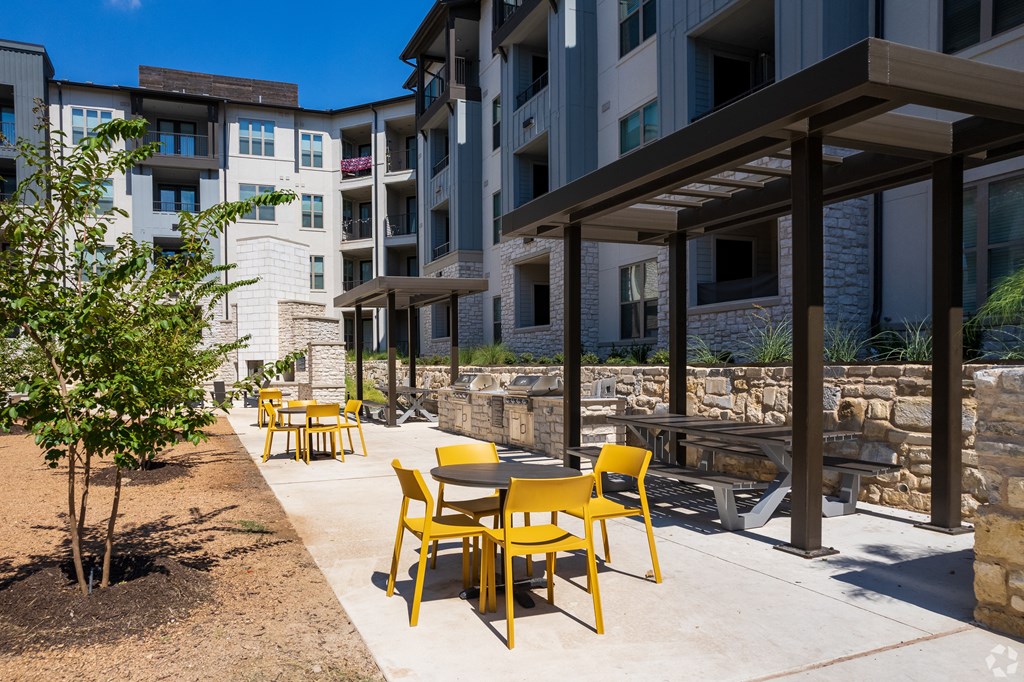 an outdoor patio with tables and chairs at an apartment complex