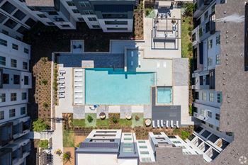 A swimming pool is surrounded by a patio and a building.