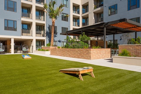 a lawn with a picnic table in front of an apartment building