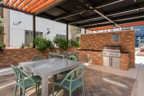 a patio with a table and chairs and an outdoor kitchen
