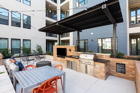 a patio with a barbecue grill and a table with chairs