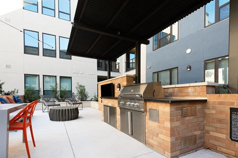 an outdoor kitchen with a grill and a table and chairs
