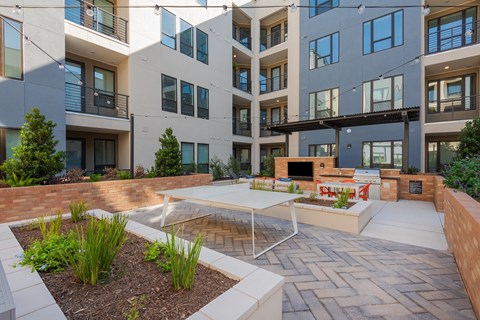 an outdoor living area with a table and chairs in front of an apartment building