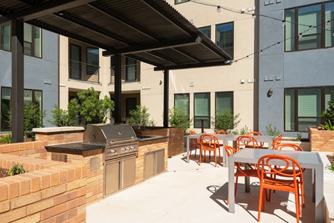a patio with a barbecue grill and tables and chairs