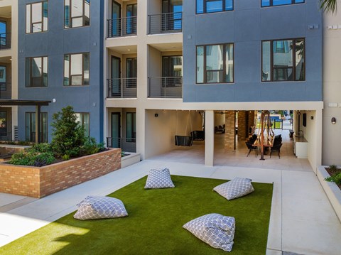 an open courtyard with pillows and grass in front of an apartment building