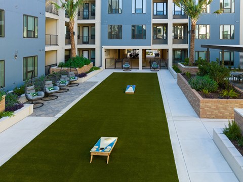 two lounge chairs on the grass in the courtyard of an apartment building