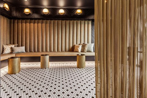 a seating area with a bench and stools on a black and white tiled floor