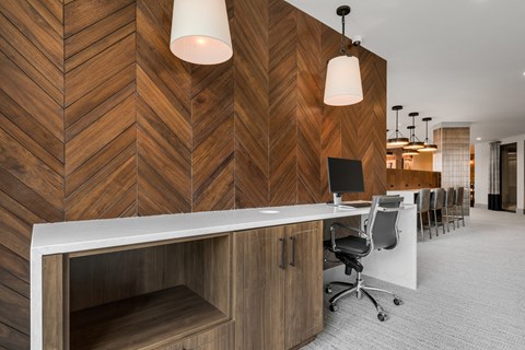 a room with a long desk with a computer on it and a wooden wall behind it