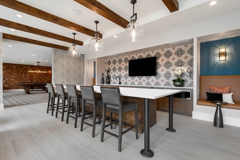 a room with a long table with chairs and a tv on the wall