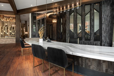 a long marble bar with black chairs and a staircase in the background