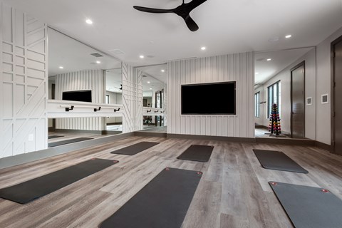 a spacious yoga room with a large flat screen tv on the wall and a row of yoga
