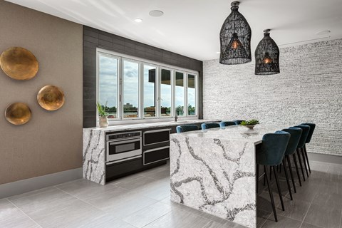 a kitchen with white marble countertops and a long island with blue chairs