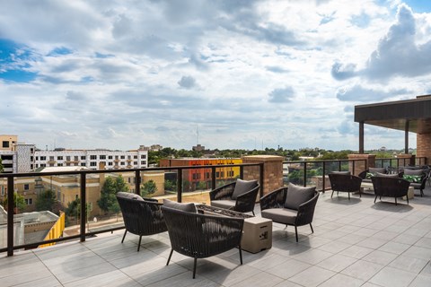 a large terrace with chairs and a table with a view of the city in the background