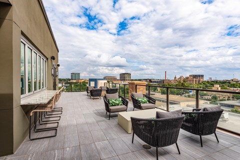 an outdoor terrace with chairs and couches with a view of the city