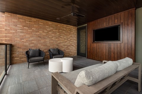 a large covered patio with a brick wall and a wooden patio table with two chairs and a