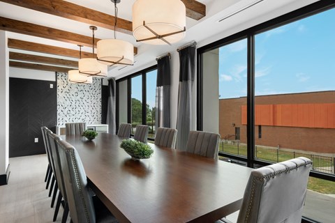 a long table with chairs in a room with large windows