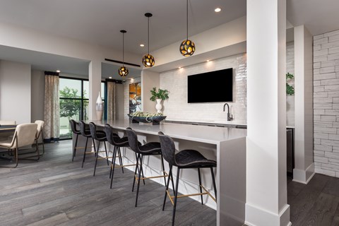 an open kitchen and dining area with a bar and chairs and a tv