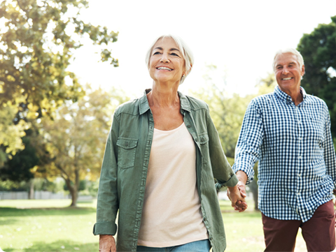 an older man and woman walking in the park