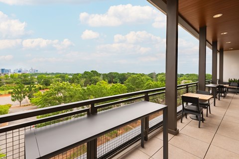 A balcony with a table and chairs overlooking a green landscape.