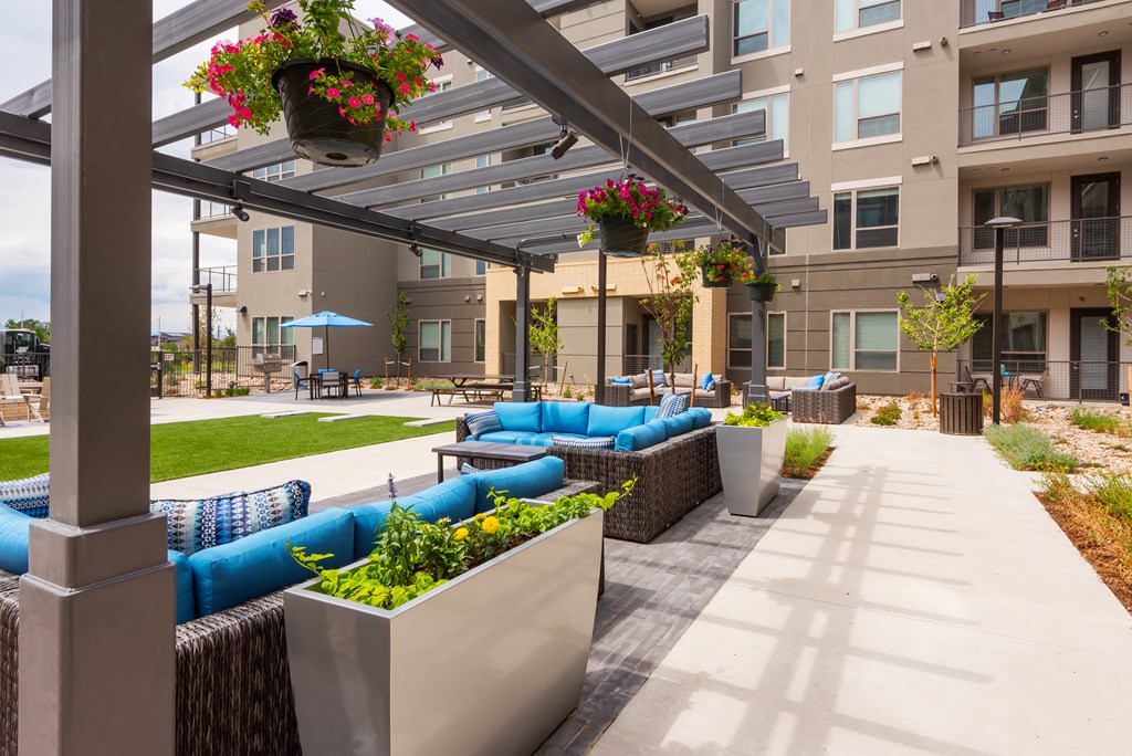 an outdoor lounge area with blue couches and a table with a blue umbrella in the background  at Encore at Boulevard One, Colorado