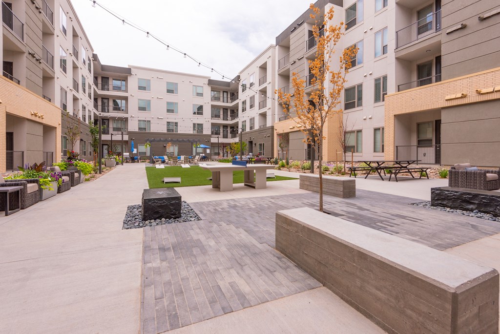 an open area with benches and trees in the middle of an apartment complex  at Encore at Boulevard One, Denver, CO
