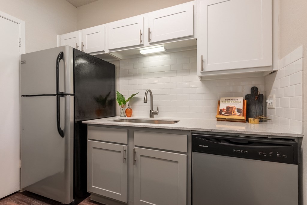 a kitchen with white cabinets and a black refrigerator