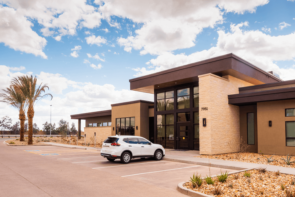 escape at arrowhead apartments denois building with a white car parked infront of the building