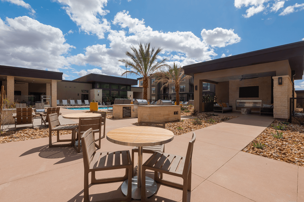 pool area with tables and chairs at escape at arrowhead's apartments in glendale, az