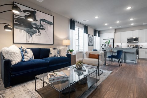 A modern living room with a dark blue sofa and a glass coffee table.