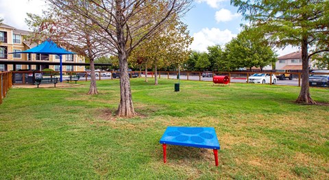 a blue ping pong table in a grassy area with a building in the background