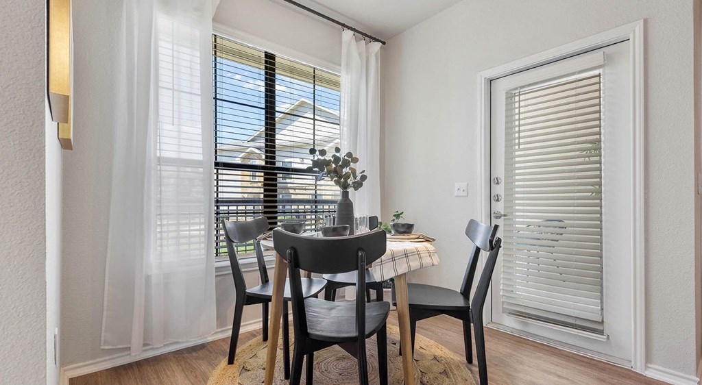a dining room with two windows and a door that leads to a balcony