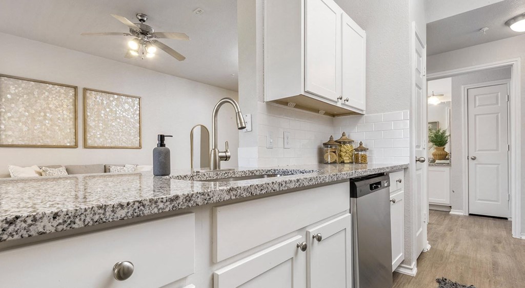 a kitchen with white cabinets and granite countertops