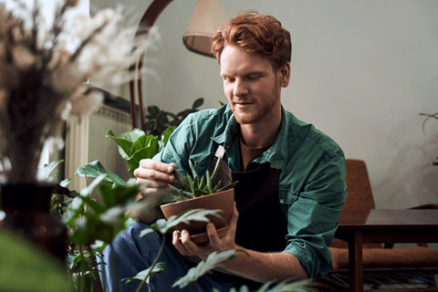 A man in a green shirt is sitting and reading a book.