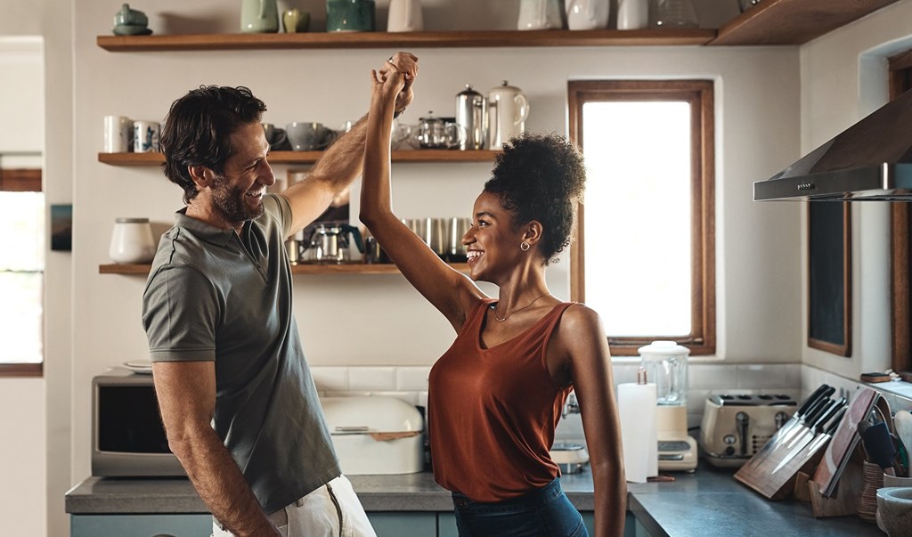 A man and a woman are dancing in a kitchen.
