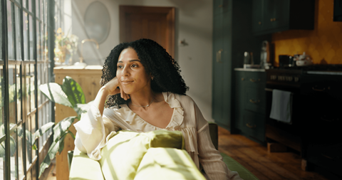A woman in a white blouse is sitting on a green couch.