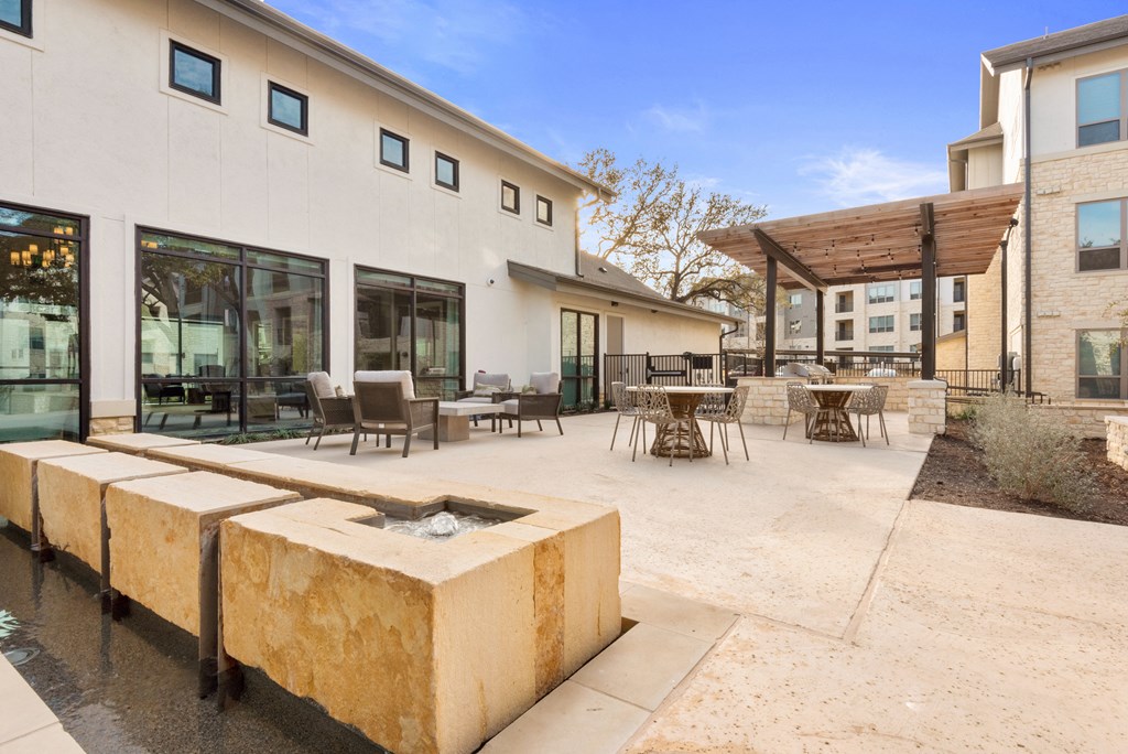 a patio with tables and chairs and a fountain outside of a building