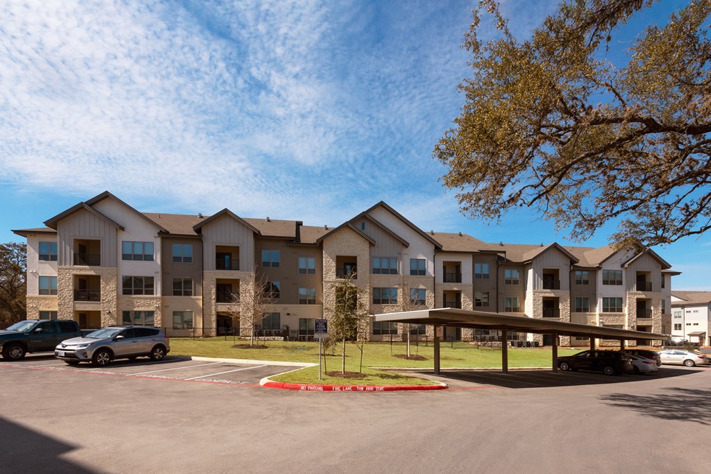 the exterior of an apartment building with cars parked in a parking lot