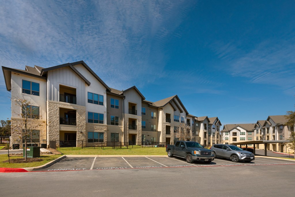 a parking lot with cars in front of an apartment building