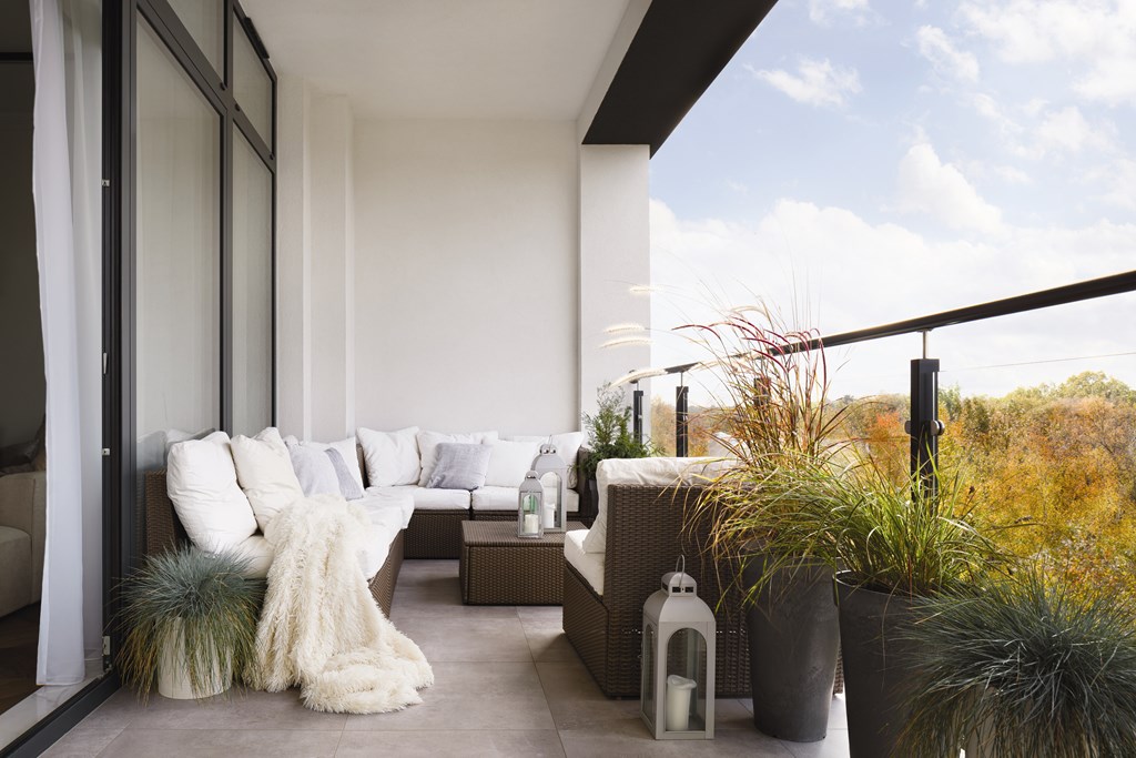 A modern outdoor living space with a couch, pillows, and plants.